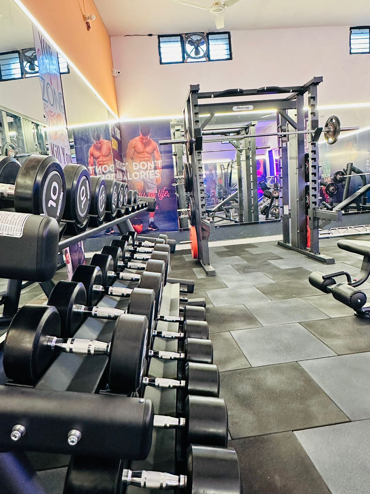 Dumbbells and a squat rack inside D Fitness Gym